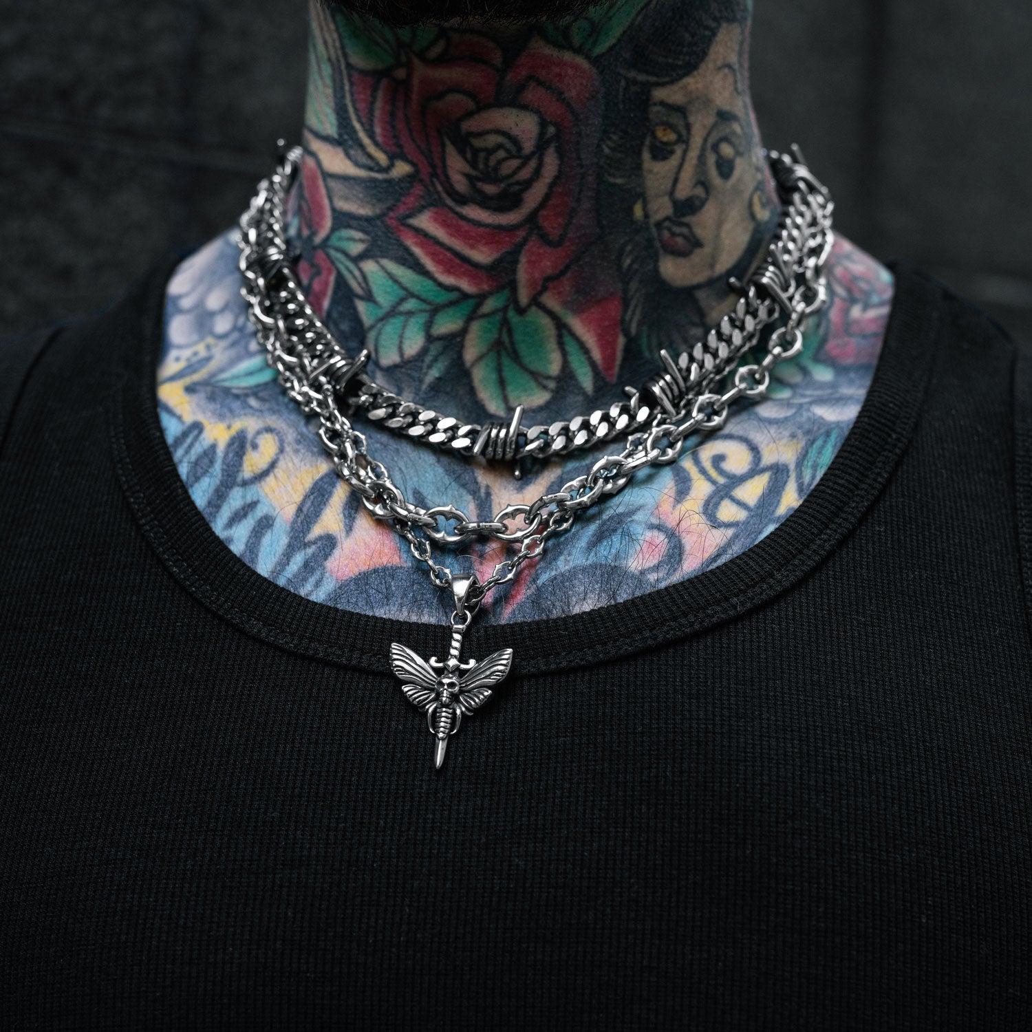 Gothic silver chain set with moth and dagger pendant and barbed wire chain on mans neck by Statement Collective