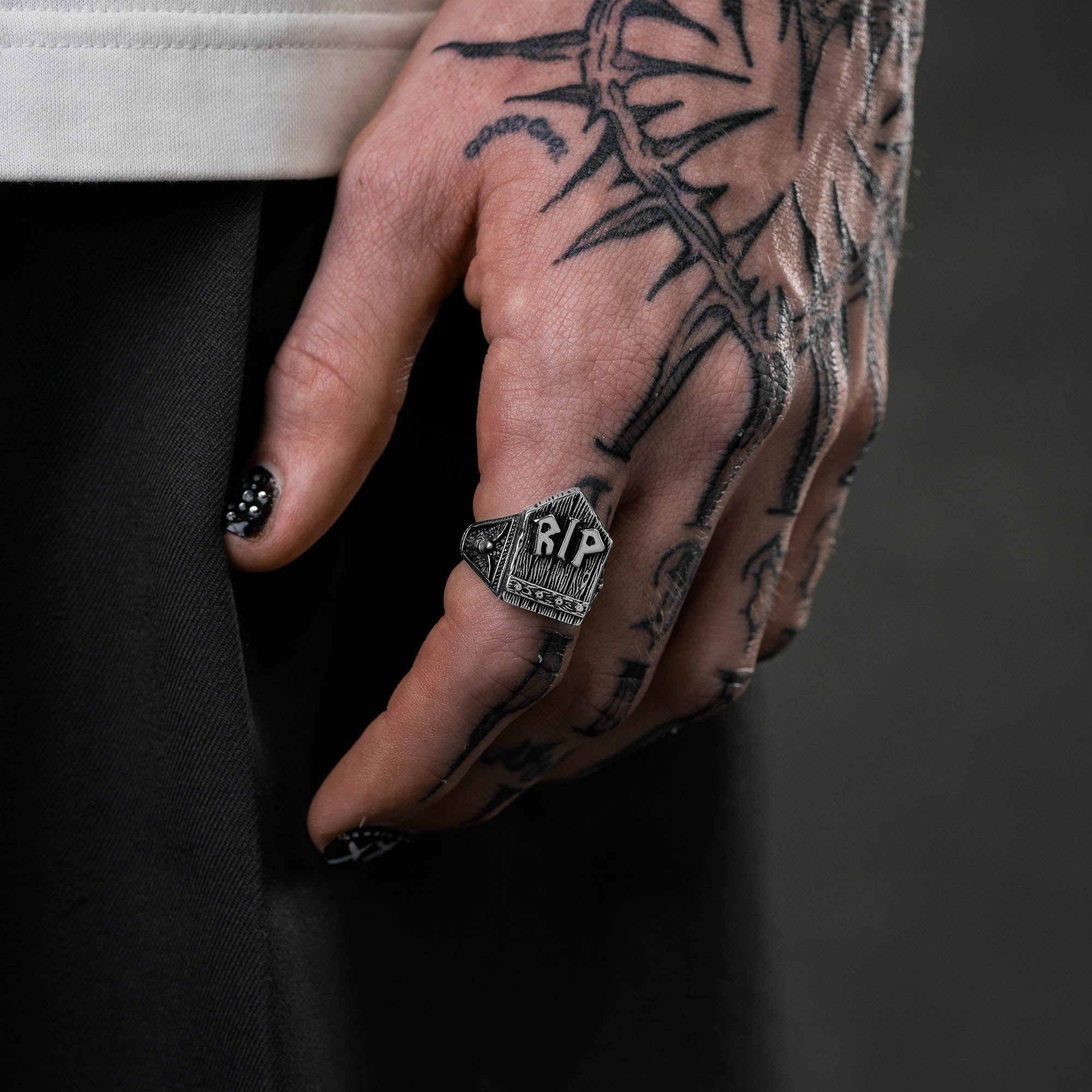 Silver gravestone ring, chunky, with "RIP" embedded at the top of gravestone on male hand with tattoos