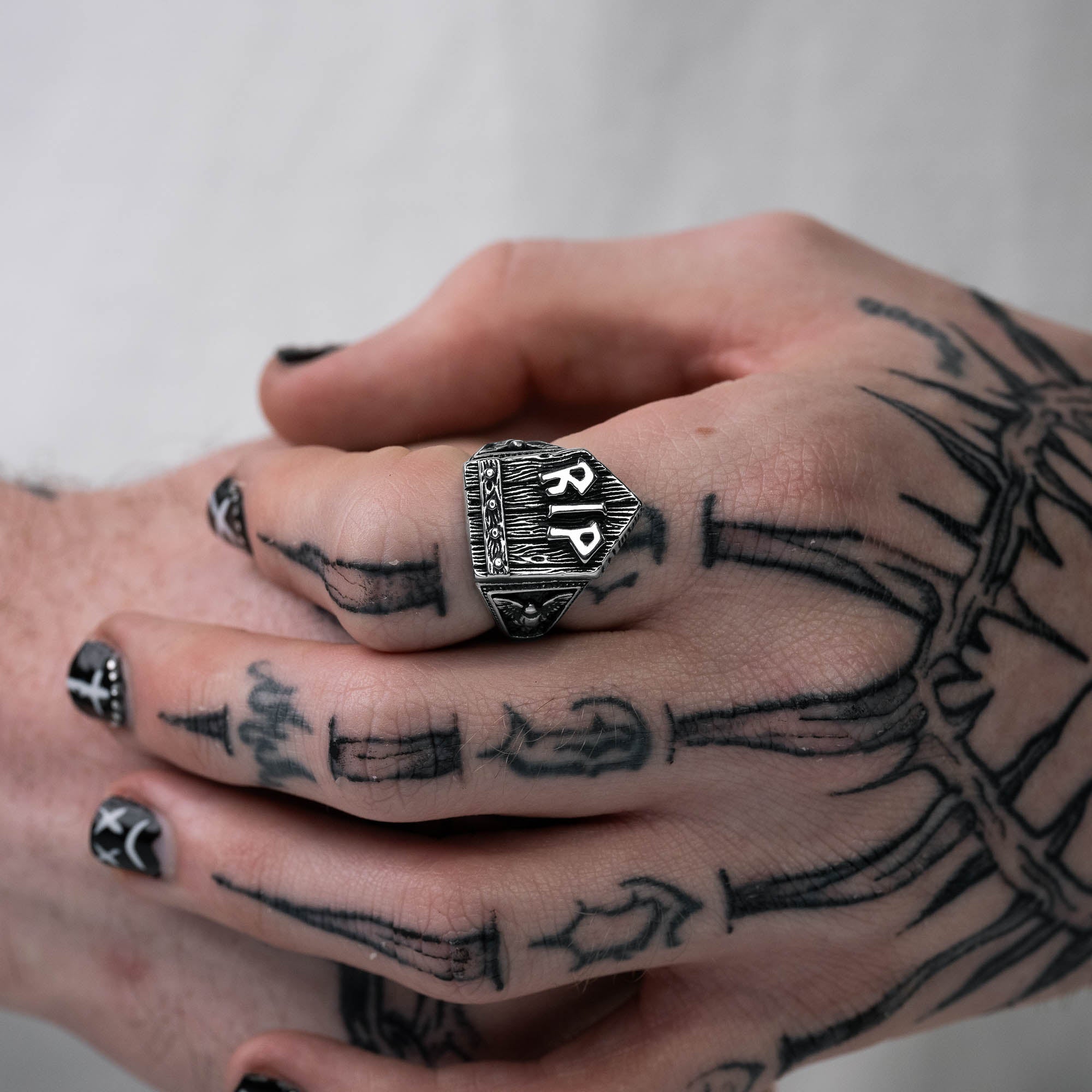 Silver gravestone ring, chunky, with "RIP" embedded at the top of gravestone, on male hand with tattoos