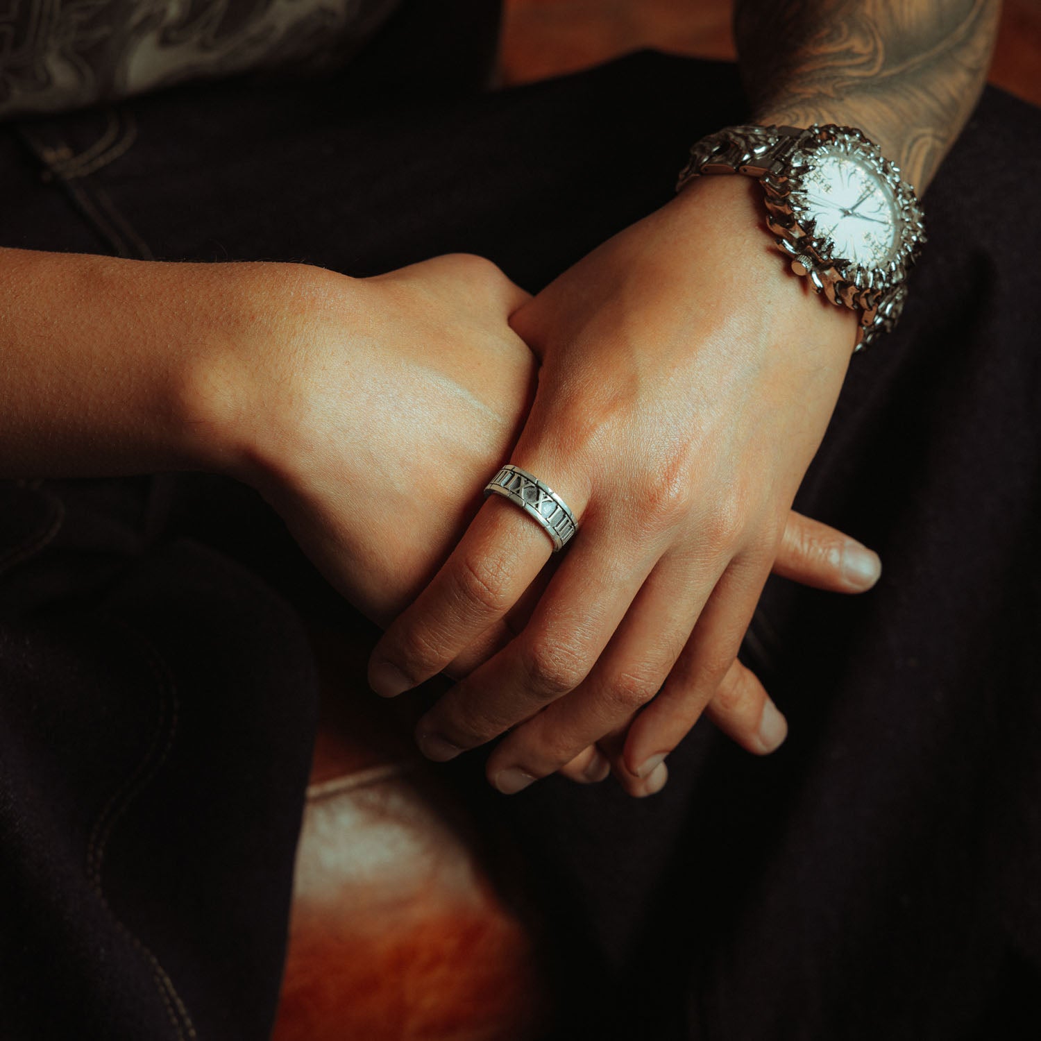 Sterling Silver band ring with roman numerals the entire way around it on male hand 