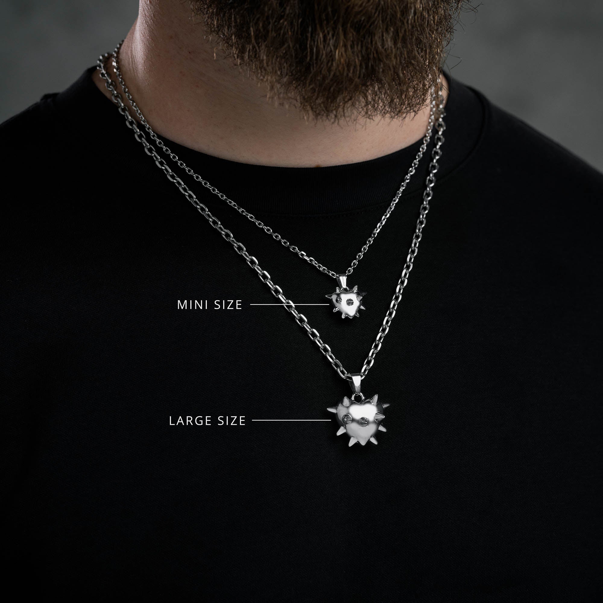 Silver Spiked heart pendants on 2 cable chains in different widths showing our mini size spiked heart against a larger sized spiked heart on male model with Black t shirt