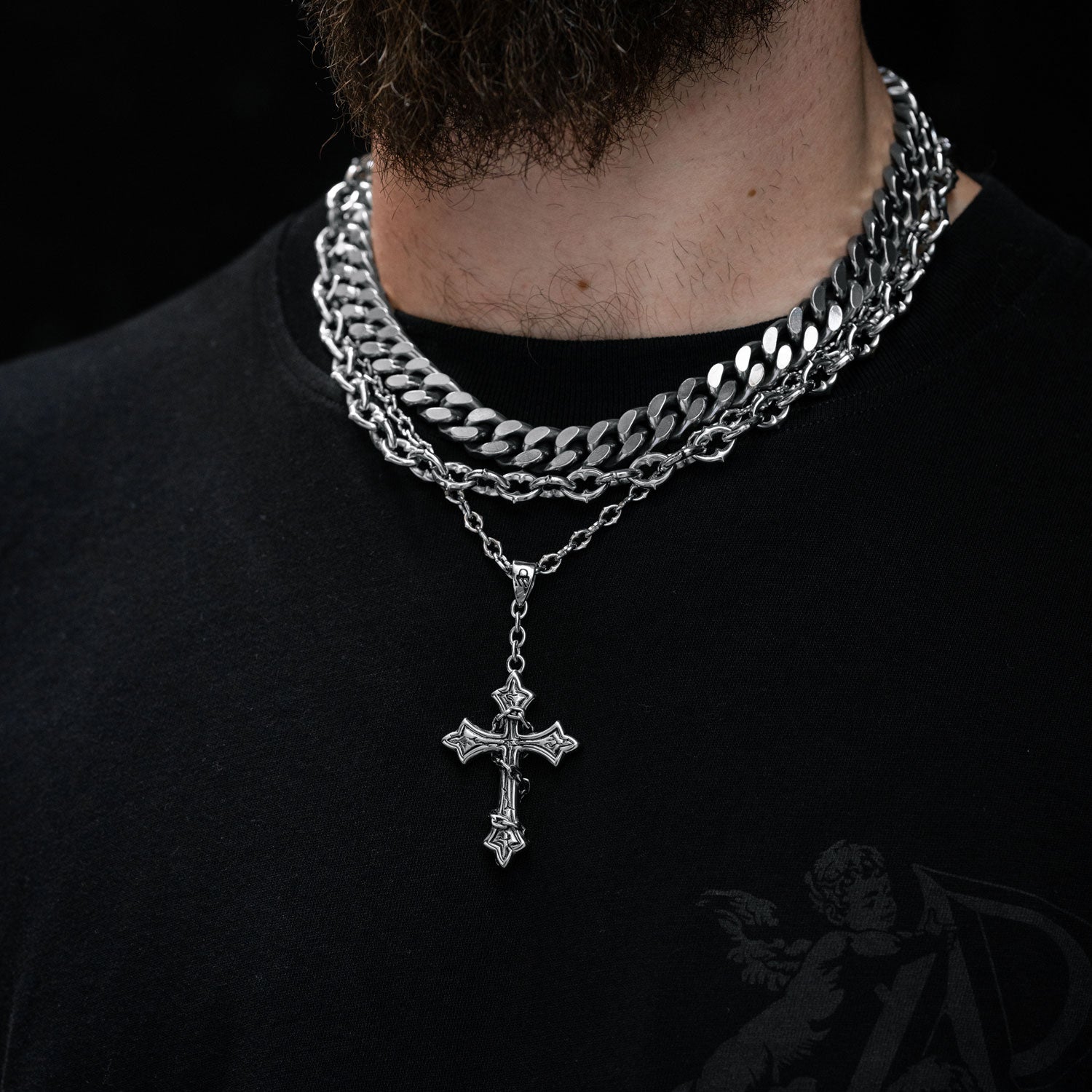 Gothic silver necklace set with spiked chain and cross pendant on mans neck by statement collective